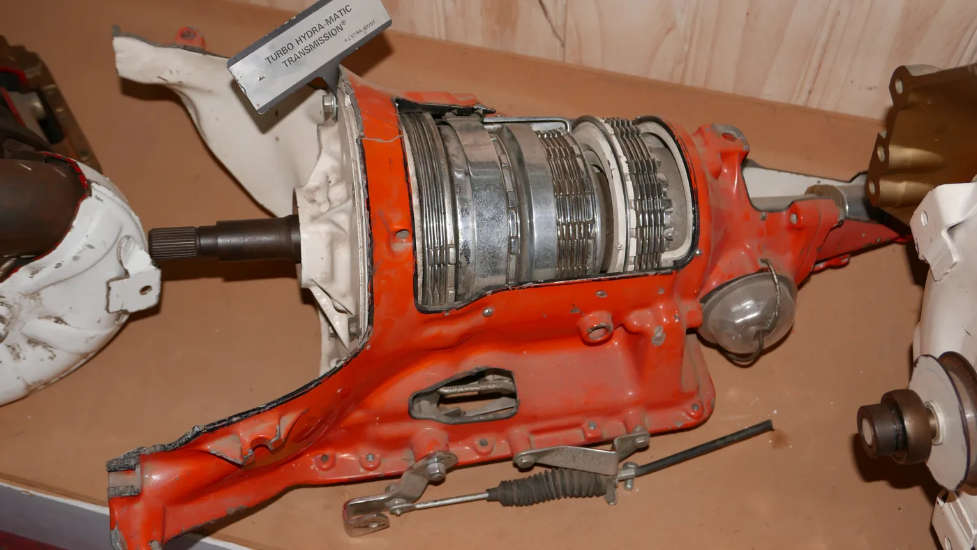 Cutaway of an orange three-speed GM Turbo Hydra-Matic automatic transmission on a museum display table