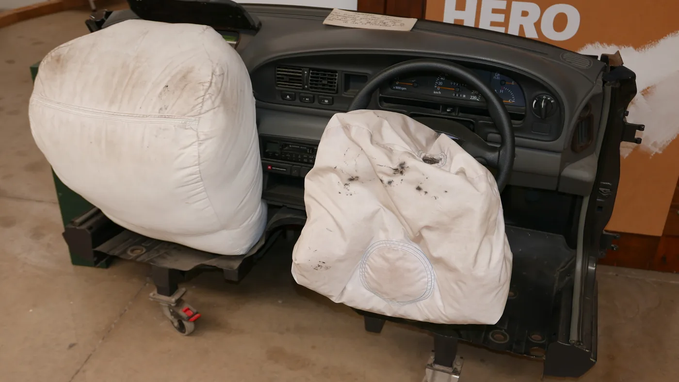Deployed driver and passenger front air bags hanging from a dashboard display in a museum exhibit