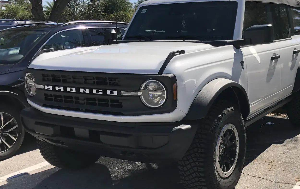 White four-door Ford Bronco SUV with black fender flares parked in a lot, seen from the front left