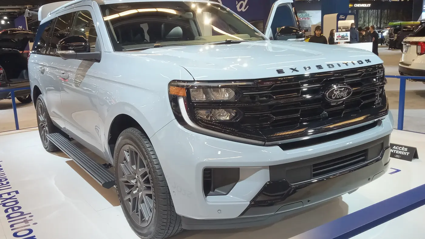 Light blue-white 2025 Ford Expedition Max at an auto show, showing LED headlight and daytime running light strips