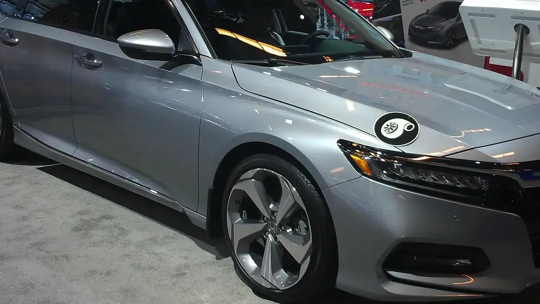 Silver 2018 Honda Accord Touring sedan on display at an auto show, seen from the front right
