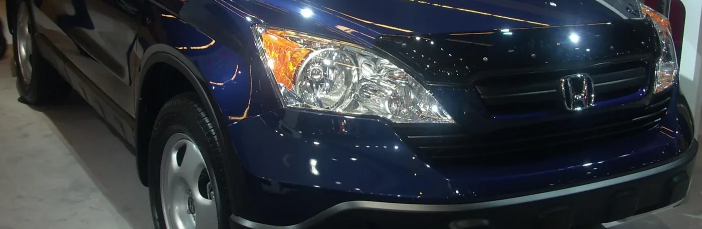 Close-up of the front of a dark blue 2009 Honda CR-V with chrome headlight and grille on show at an auto show