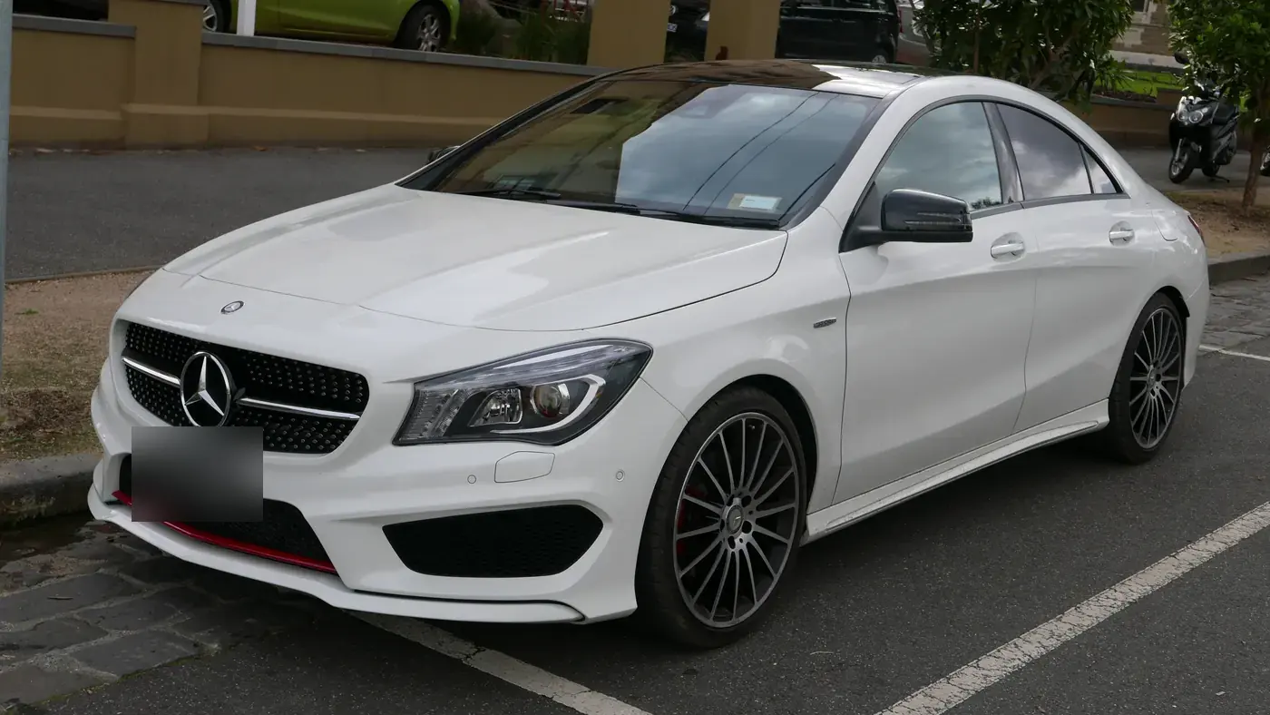 White Mercedes-Benz CLA 250 sedan of the C117 generation parked at a curb, seen from the front left