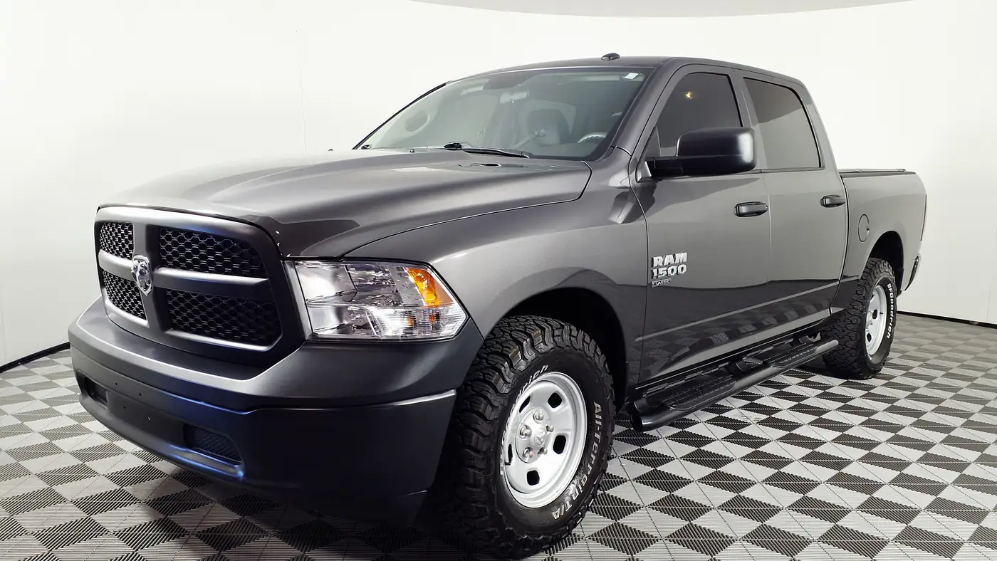Gray 2023 Ram 1500 Classic Tradesman crew cab pickup in a showroom, seen from the front left with its side mirror visible