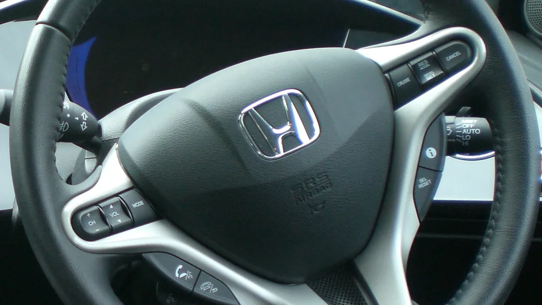Driver's steering wheel with the SRS AIRBAG cover in the hub, between the cruise and audio control buttons