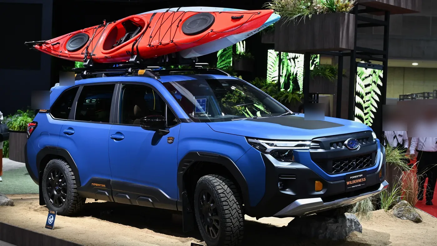 Blue Subaru Forester Wilderness prototype SUV with a red kayak on the roof rack, shown on a display stand at an auto show