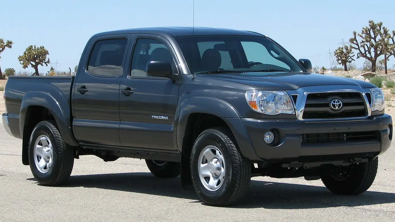 Gray 2009 Toyota Tacoma PreRunner double cab pickup parked on pavement with Joshua trees behind it