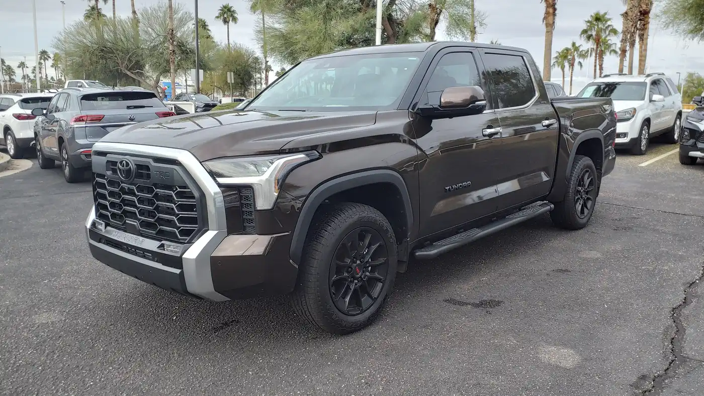 Dark brown 2022 Toyota Tundra Limited crew-cab pickup parked on a dealer lot with palm trees behind